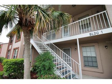 Building 1 shows a exterior stairway, tropical landscaping, and neutral paint at 6338 Spring Flower Dr # 21, New Port Richey, FL 34653