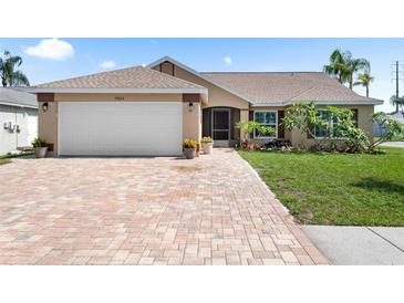Charming single-story home featuring a brick driveway and attached two-car garage at 7923 Woburn St, New Port Richey, FL 34653