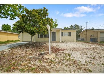 Modest single-story home with a small yard, partial stone ground cover, and mature shade tree at 8053 Dedham Dr, Port Richey, FL 34668