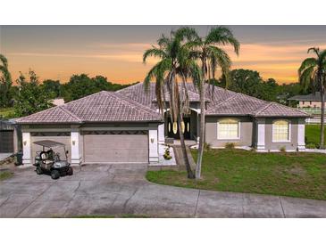 Charming single Gathering home featuring a well-manicured lawn, a tile roof, and an attached three car garage at 10941 Hilltop Dr, New Port Richey, FL 34654