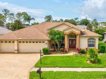 Charming single-story home featuring a well-manicured lawn, a three-car garage, and a welcoming front entrance at 11144 Brambleleaf Way, Hudson, FL 34667