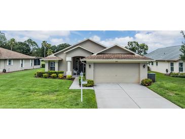 Charming single-story home with a well-maintained lawn, mature landscaping, and a two-car garage at 1242 Almondwood Dr, Trinity, FL 34655