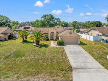 Charming single-story home featuring a well-maintained lawn, mature trees, and a spacious driveway leading to a two-car garage at 13491 Coronado Dr, Spring Hill, FL 34609