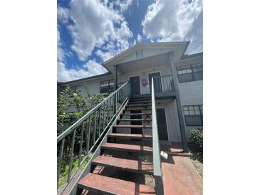 Two story condo building featuring stairs to second floor units and a gray exterior at 203 Pine Violet Ct # 202, Tampa, FL 33612