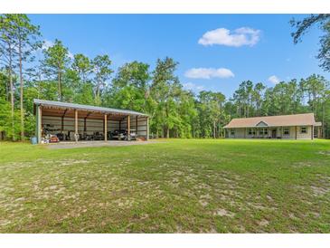 A house and large metal outbuilding are set on a large lot, surrounded by trees at 27295 Tarbel Rd, Brooksville, FL 34602