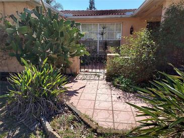 Inviting front entrance with tile walkway, mature landscaping and wrought iron gate at 3206 Pinon Dr, Holiday, FL 34691