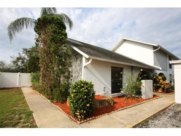Charming home exterior featuring a white facade, manicured landscaping, and a welcoming sidewalk at 6806 Beach Blvd, Hudson, FL 34667