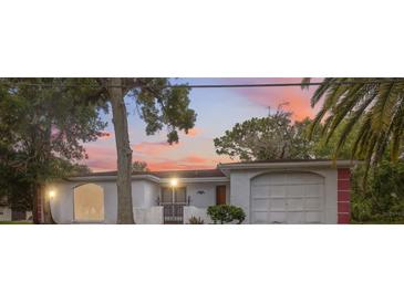 Charming home featuring unique architectural details, a well-manicured lawn, and mature trees at sunset at 8340 Saint Marks Ct, Hudson, FL 34667