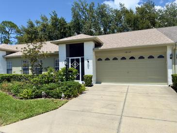 Charming single Gathering home showcasing lush landscaping and an attached two-car garage with a brick-paved driveway at 18142 Baywood Forest Dr, Hudson, FL 34667