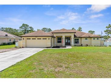 Charming single-story home featuring a well-manicured lawn and an attached two-car garage at 12026 Penguin Ave, Weeki Wachee, FL 34614