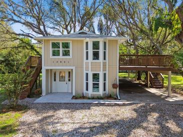 Charming two-story home featuring a light beige exterior, complemented by landscaped yard, wooden deck and lush trees at 13901 Vacation Ln, Odessa, FL 33556