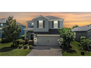 Charming two-story home featuring a well-manicured lawn, brick-paved driveway, and attached two-car garage at 1783 Oak Hammock Ct, Lutz, FL 33558
