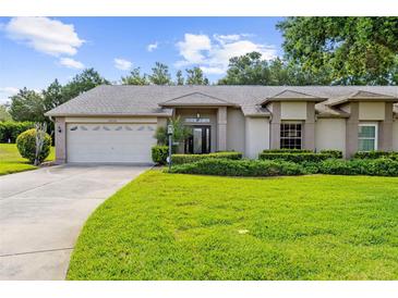 Charming home featuring a manicured lawn, complemented by lush landscaping and a two car garage at 18736 Bent Pine Dr, Hudson, FL 34667