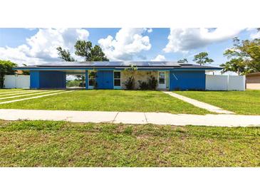 Bright blue single-story home featuring well-kept lawn, solar panels, and covered parking at 22348 Olean Blvd, Port Charlotte, FL 33952
