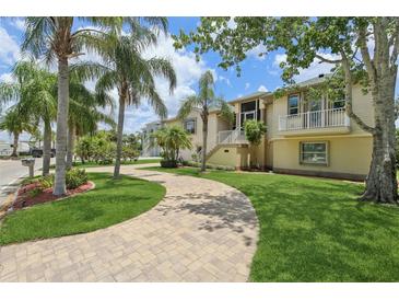 Charming home featuring lush landscaping, a paver driveway, and a welcoming facade under a sunny sky at 4052 Marine Pkwy, New Port Richey, FL 34652