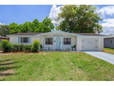 Charming single-Gathering home featuring a well-manicured lawn, blue trim, front porch, and attached garage at 6144 Glenwood Dr, New Port Richey, FL 34653
