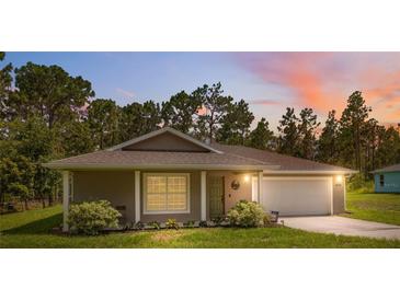 Charming single-story home featuring a two-car garage, well-manicured lawn, and a cozy front porch at 11034 Flock Ave, Weeki Wachee, FL 34613