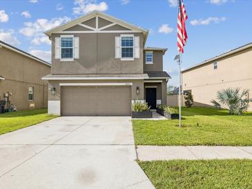Two-story home featuring a two-car garage, manicured lawn, and a welcoming front entrance with an American flag at 14000 Lugano Ct, Hudson, FL 34669