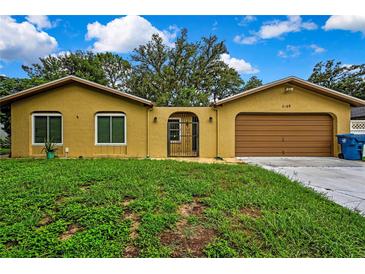 Cozy single-story home featuring a two-car garage, gated entrance, and bright yellow stucco at 2169 Danforth Rd, Spring Hill, FL 34608