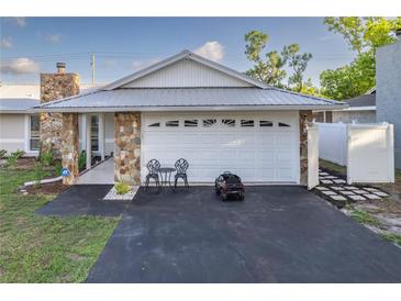 Charming home featuring stone accents, a metal roof, and a freshly paved driveway leading to an attached two-car garage at 5520 Fulmar Dr, Tampa, FL 33625