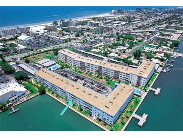 Aerial view of a waterfront condo complex with boat docks, pool, and parking, near the beach in a coastal neighborhood at 5555 Gulf Blvd # 315, St Pete Beach, FL 33706