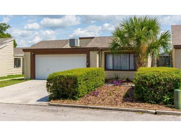 Cozy home featuring an attached garage, well-maintained landscaping, and a beautiful palm tree accenting the front yard at 7412 Bellows Falls Ln, Hudson, FL 34667