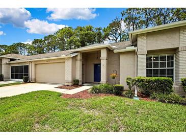 Charming single-story home featuring a blue front door, attached garage, and well-maintained landscaping at 7423 Woodhollow Rd, Spring Hill, FL 34606