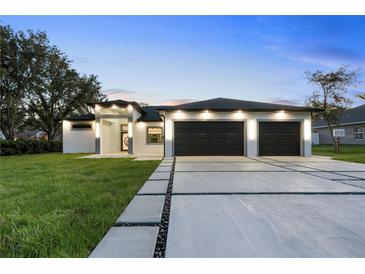 Stunning contemporary home featuring a manicured lawn, wide driveway, and a stylish two-car garage at 9201 Nightingale Rd, Weeki Wachee, FL 34613