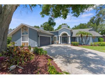 Charming blue single-Gathering home with arched entryway, well-manicured landscaping, and a spacious driveway at 1430 Rosetree Ct, Clearwater, FL 33764