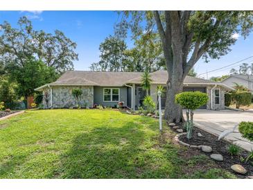 Charming single-story home featuring stone accents and a well-manicured lawn with mature landscaping at 2295 Rio Cir, Spring Hill, FL 34608