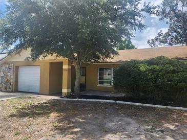 Charming single-story home featuring a stone accent wall, covered entryway, and attached garage at 7338 Foxbloom Dr, Port Richey, FL 34668
