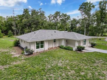 An attractive exterior view of the home with a new roof, lush lawn and mature trees, creating a desirable curb appeal at 10097 Weatherly Rd, Brooksville, FL 34601