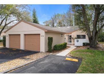 Charming villa with a two-car garage, tidy landscaping, and a welcoming gated front entry at 13134 Cypress Hill Dr, Hudson, FL 34669