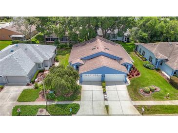 Charming blue home with a two-car garage, landscaped front yard, and mature landscaping at 13321 Norman Cir, Hudson, FL 34669
