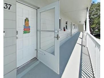 Front door of property #37, featuring a decorative pineapple and access to a shared balcony walkway at 2261 Swedish Dr # 37, Clearwater, FL 33763