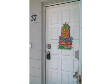 Inviting front door with a decorative pineapple, 'food, music, fun' sign, and visible unit number at 2261 Swedish Dr # 37, Clearwater, FL 33763