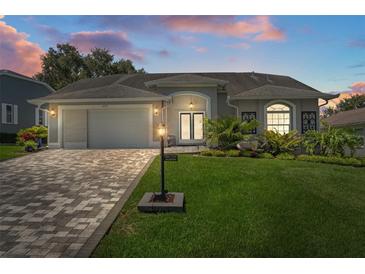 Charming single-story home featuring a paved driveway, lush lawn, and meticulously landscaped front yard at 2275 Terrace View Ln, Spring Hill, FL 34606