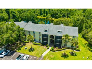 Condo building with beautiful landscaping, pond view, and ample parking at 3134 Lake Pine Way # F2, Tarpon Springs, FL 34688