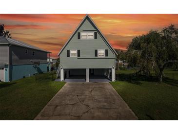 A-frame stilt home with green siding, black shutters, and covered parking area at ground level at 3363 Poinsettia Dr, Hernando Beach, FL 34607