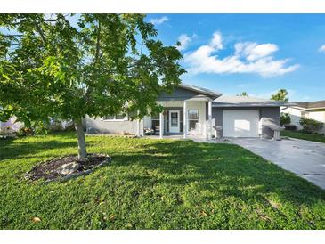 Charming single-story home with a well-manicured lawn and a tree in the front yard at 7118 Cherry Laurel Dr, Port Richey, FL 34668