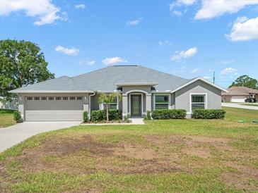 Charming single-story home with a well-maintained lawn and a two-car garage and decorative shrubs along the front of the house at 8199 Nordica Rd, Weeki Wachee, FL 34613