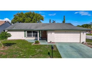 Charming single-story home featuring a well-maintained lawn, classic brick facade, and an attached two-car garage at 9425 Sterling Ln, Port Richey, FL 34668