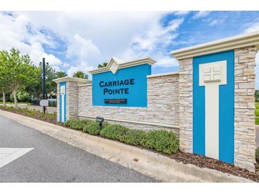 Attractive entrance sign for Carriage Pointe featuring manicured landscaping and a stacked stone and blue sign at 12119 Barnsley Reserve Pl, Gibsonton, FL 33534