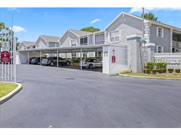 View of covered parking spaces at The Hillside community with grey condo buildings on a bright, sunny day at 12141 Spartan Way # 102, Hudson, FL 34667