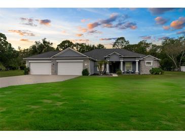 Charming single Gathering home featuring a well-manicured lawn, 3-car garage and inviting front porch at 2111 Maximilian Ave, Spring Hill, FL 34609