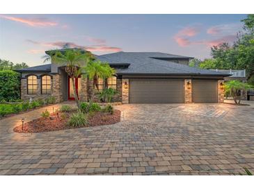 Stunning home featuring a three-car garage, stone accents, and lush landscaping at 26221 Pheasant Run, Wesley Chapel, FL 33544