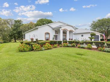 Charming single-story home featuring lush landscaping with flower beds at 489 Tournament Dr, Spring Hill, FL 34608