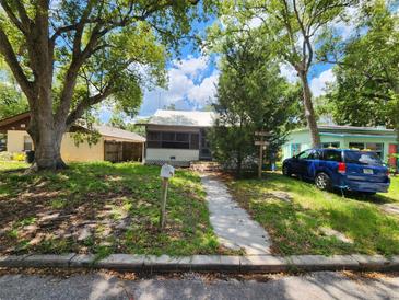 Quaint single-story home featuring a screened front porch and mature trees at 5748 Montana Ave, New Port Richey, FL 34652