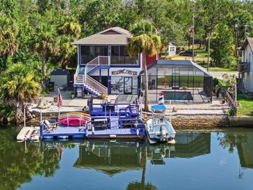 Stunning waterfront home featuring a private dock, boat lift, and screened pool, perfect for enjoying the water at 6241 Colony Cir, Weeki Wachee, FL 34607