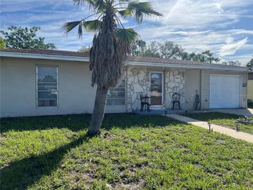 Charming single-story home featuring a stone facade, a welcoming front yard with a palm tree, and a cozy seating area at 6345 Spring Hill Dr, Spring Hill, FL 34606